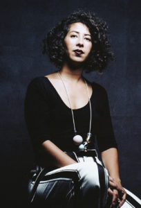 picture of assia bounadoui, sitting with hands in lab, slight smile